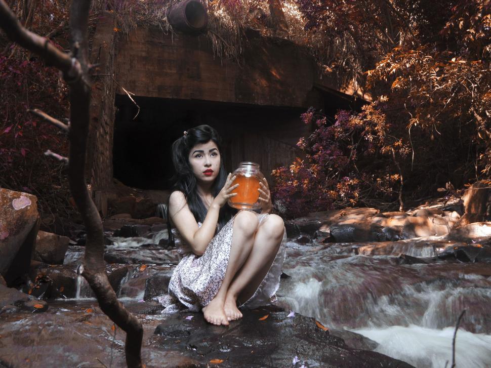 Free Image of Woman Sitting on a Rock With a Can of Soda 