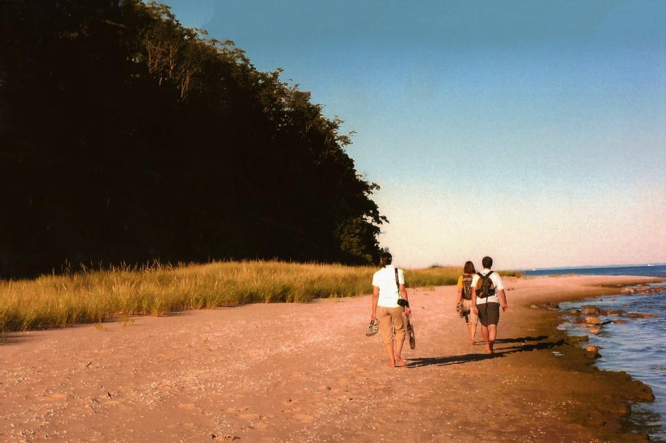 Free Image of Two People Walking on a Beach by the Ocean 
