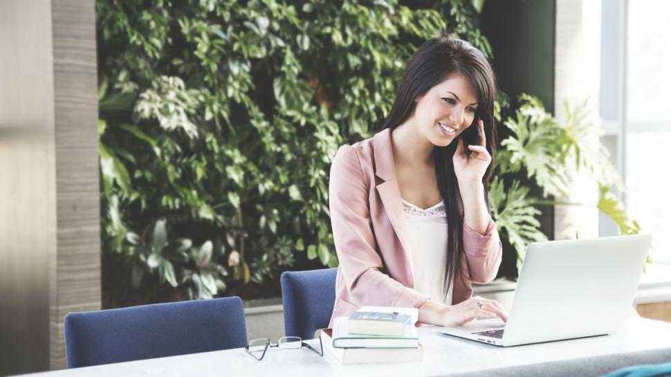 Free Image of Woman Sitting at Table Talking on Cell Phone 