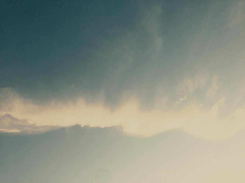 Free Image of Plane Flying Through Cloudy Sky With Mountains in Background 