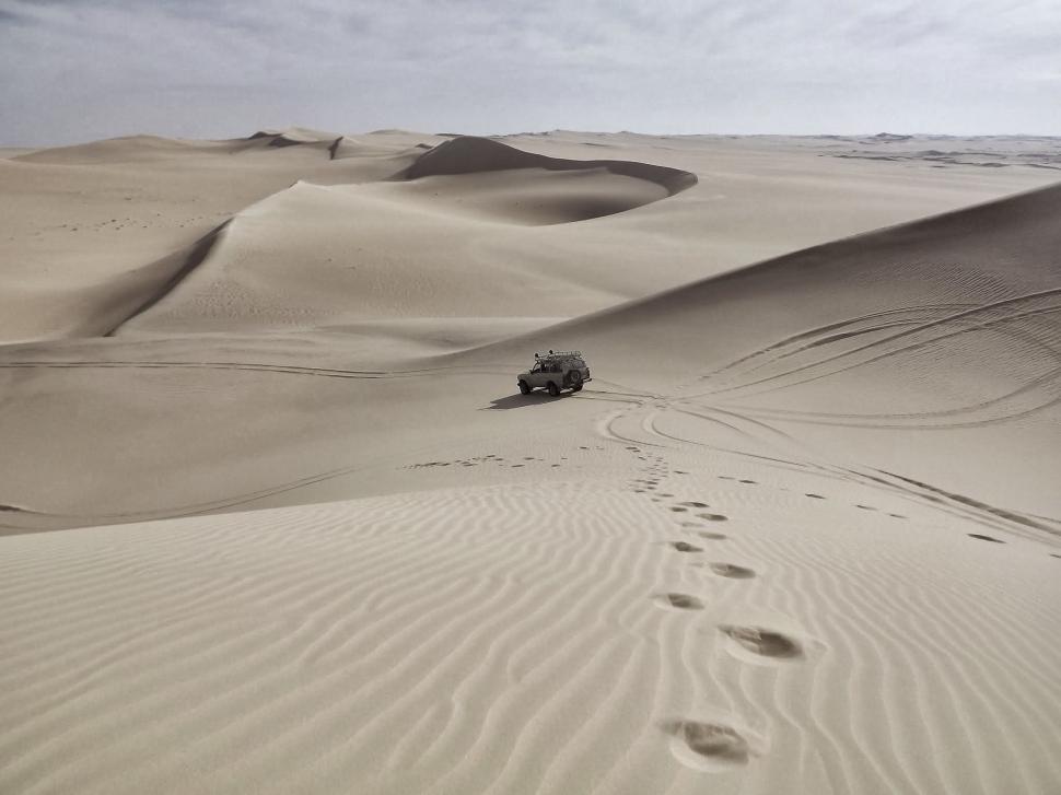Free Image of Jeep Driving Through Desert With Tracks in Sand 