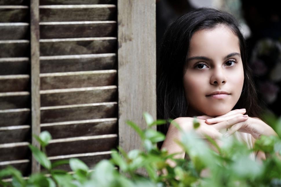 Free Image of Woman Leaning on Window Sill With Hand on Chest 