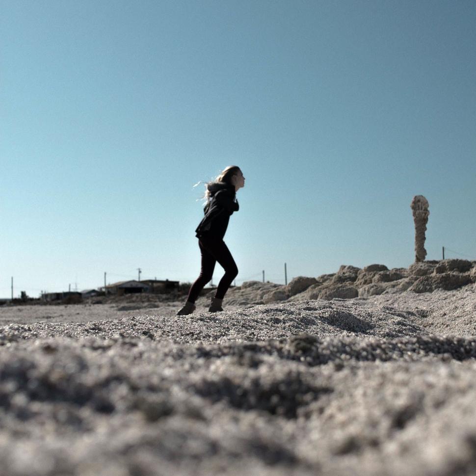 Free Image of Woman Running in Desert With Sky Background 