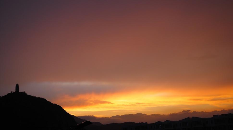 Free Image of Person Standing on Top of Hill Under Cloudy Sky 