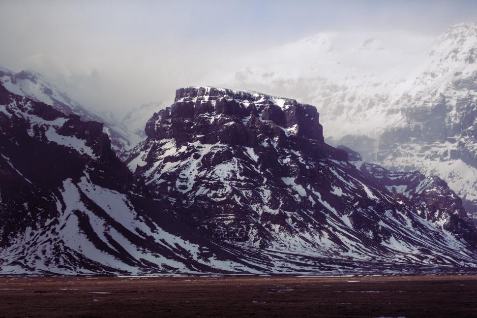 Free Image of Snow-Covered Mountain Range Under Cloudy Sky 