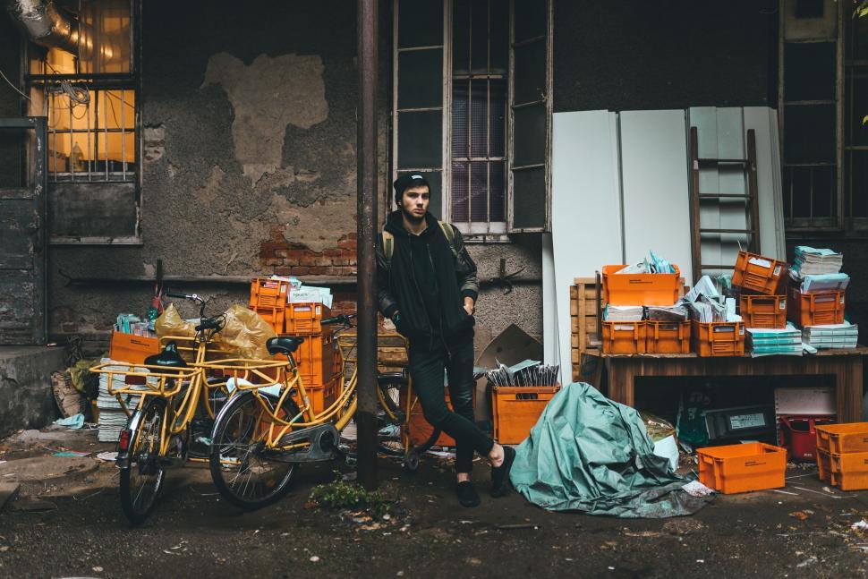 Free Image of Man Standing Next to Bike in Front of Building 