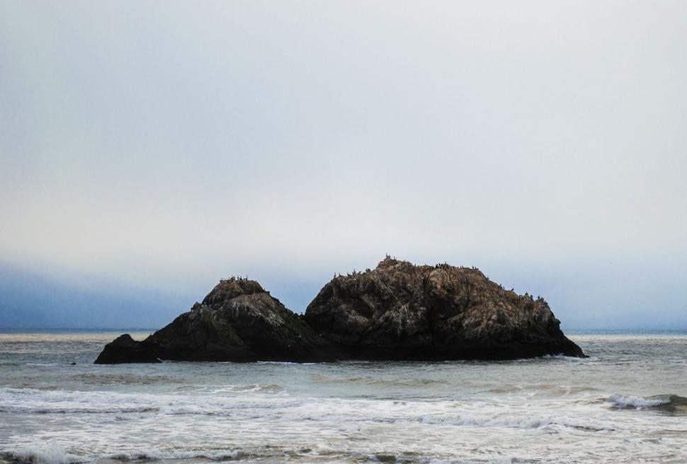 Free Image of Large Rock in the Middle of a Body of Water 