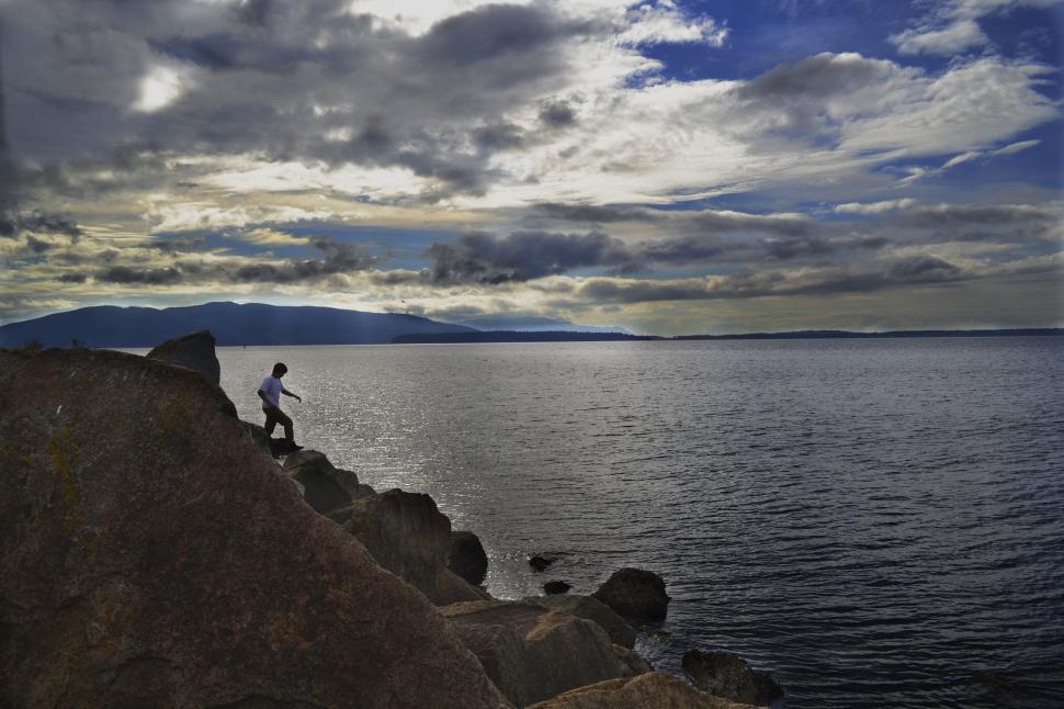 Free Image of Man Standing on Cliff Next to Water 