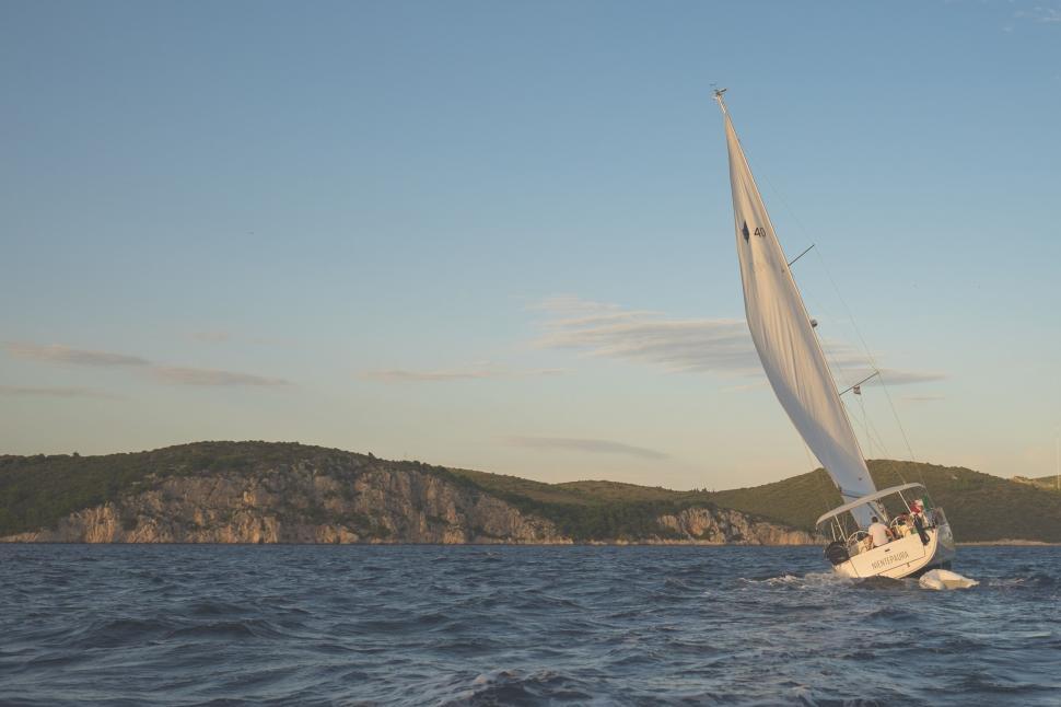 Free Image of Sailboat Sailing in Ocean With Mountain in Background 