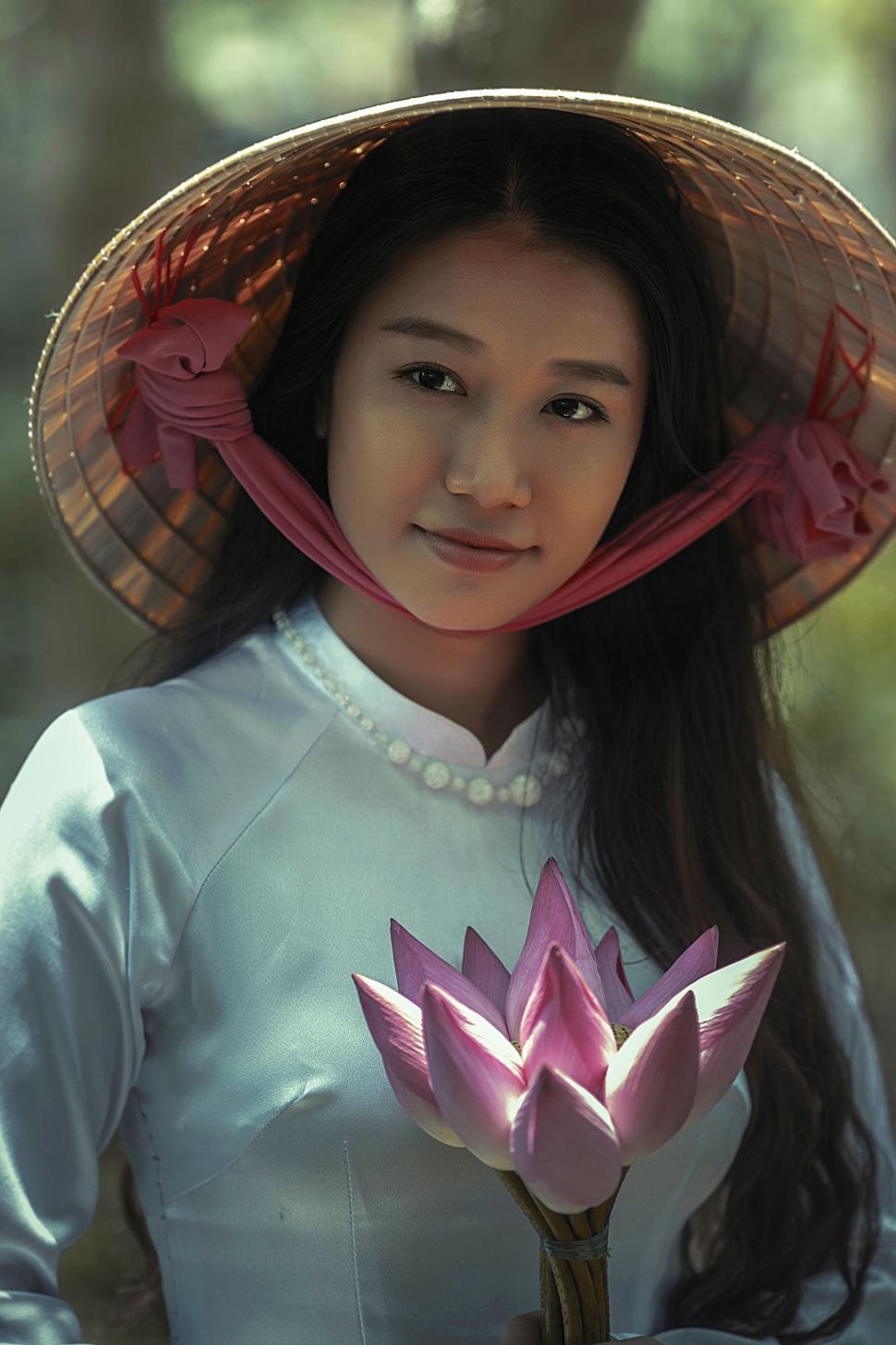 Free Image of Woman Wearing Hat Holding Flower 