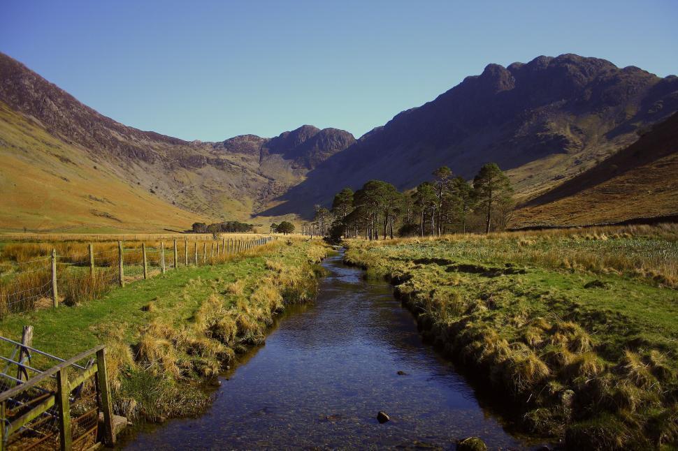 Free Image of A Stream Flowing Through a Lush Green Valley 