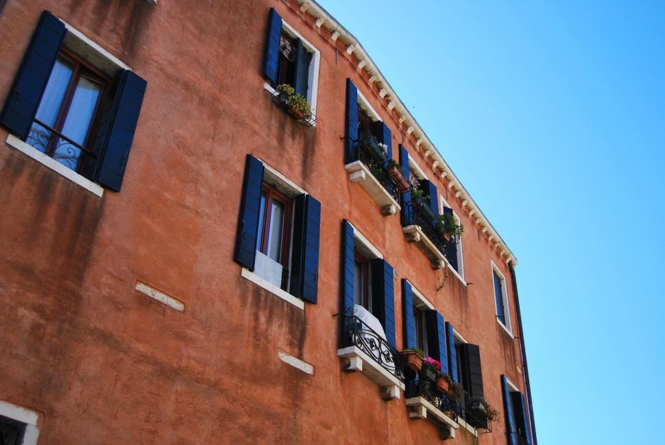 Free Image of Tall Building With Blue Shutters and Windows 