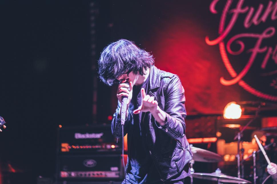 Free Image of Man Standing on Stage Holding Microphone 