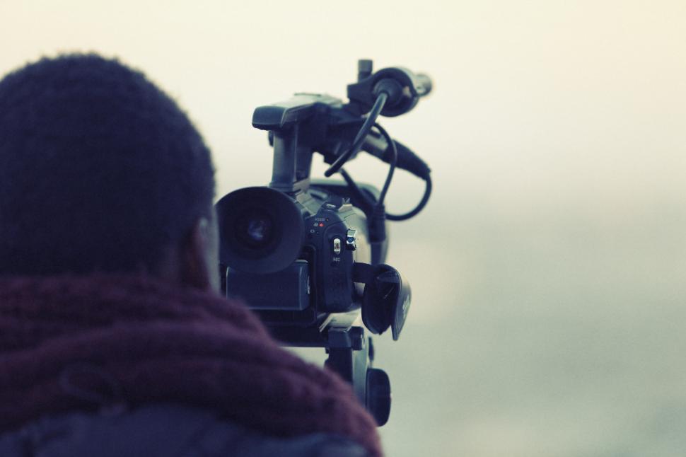 Free Image of Man Holding Camera in Front of Cloudy Sky 