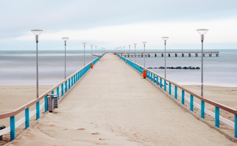 Free Image of Blue and White Fence, Light Poles, and Body of Water 