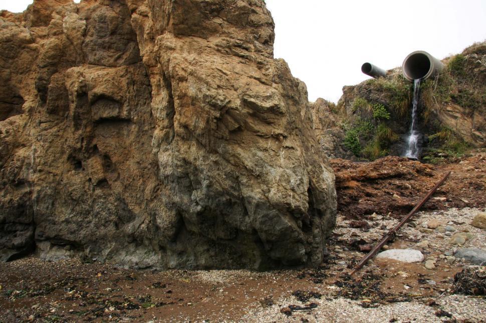 Free Image of Pipe Protruding From Rocks 