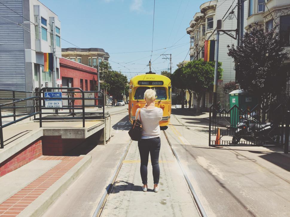 Free Image of Woman Walking Next to Yellow Bus on Street 