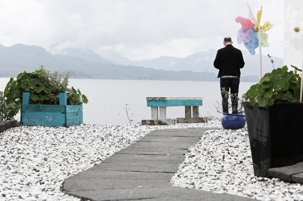 Free Image of Man Standing on Walkway Next to Body of Water 