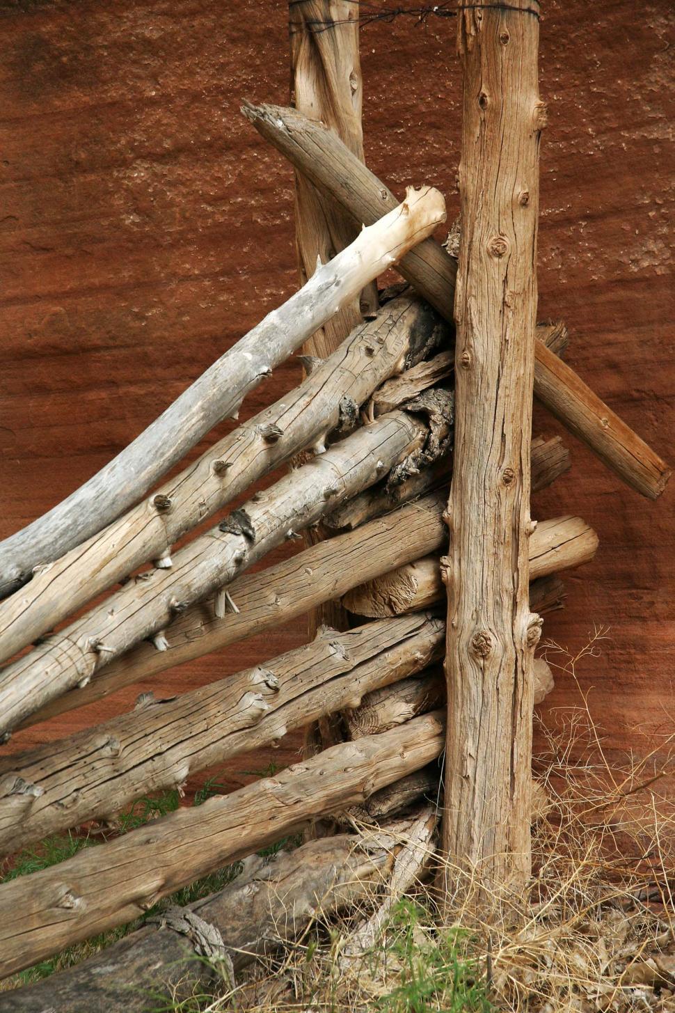 Free Image of Wooden Fence of Logs in Front of Brown Wall 