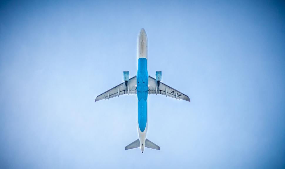 Free Image of Blue and White Jet Flying Through Blue Sky 