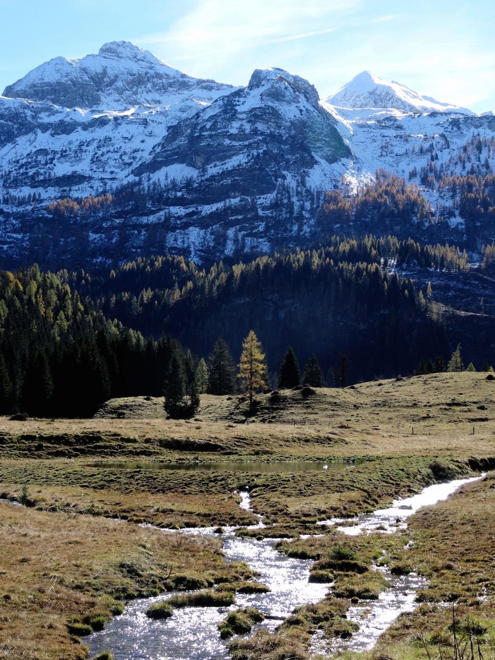 Free Image of Stream Flowing Through Grassy Field With Mountains in Background 