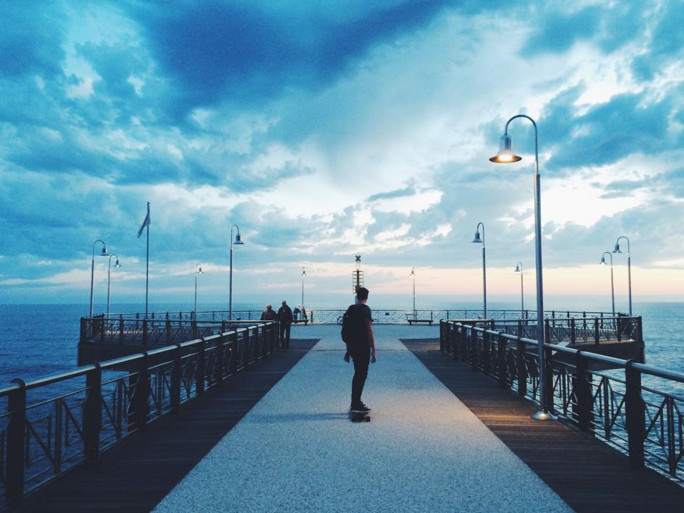 Free Image of Man Riding Skateboard Down Pier Next to Ocean 