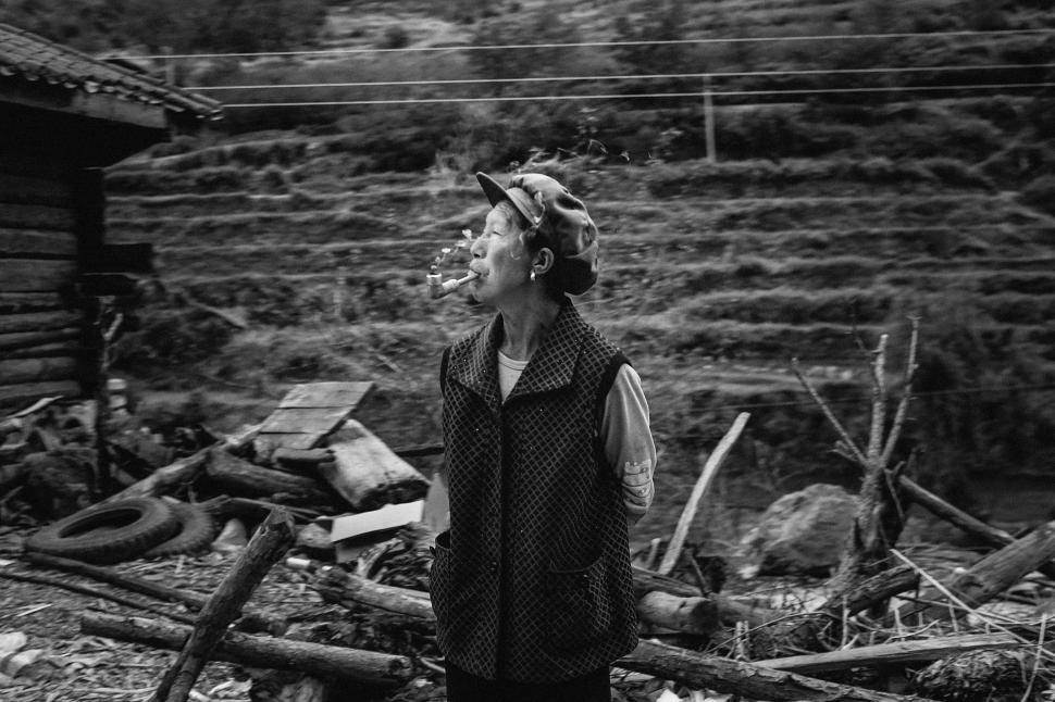Free Image of Man Standing in Front of Pile of Wood 