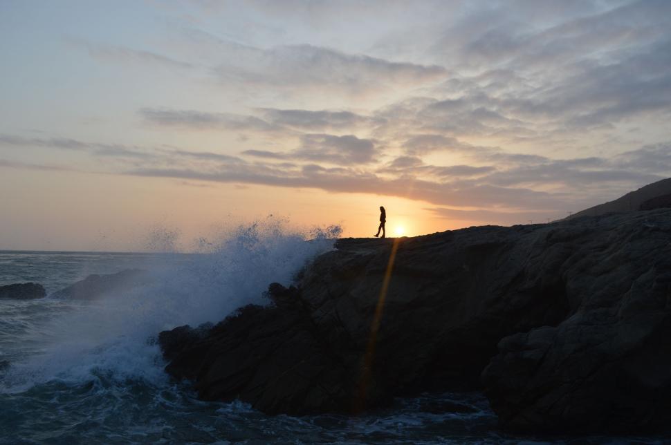 Free Image of Person Standing on Top of Rock Near Ocean 