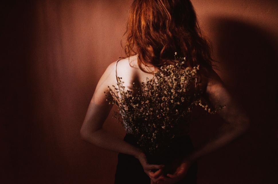 Free Image of Woman Holding Bouquet of Flowers in Dark Room 