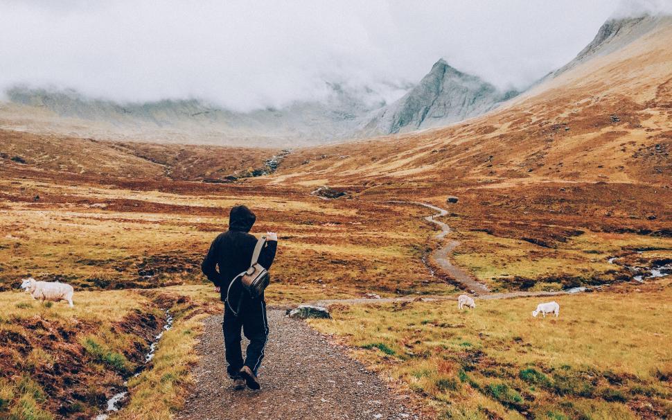 Free Image of Man Walking Down a Mountain Path 