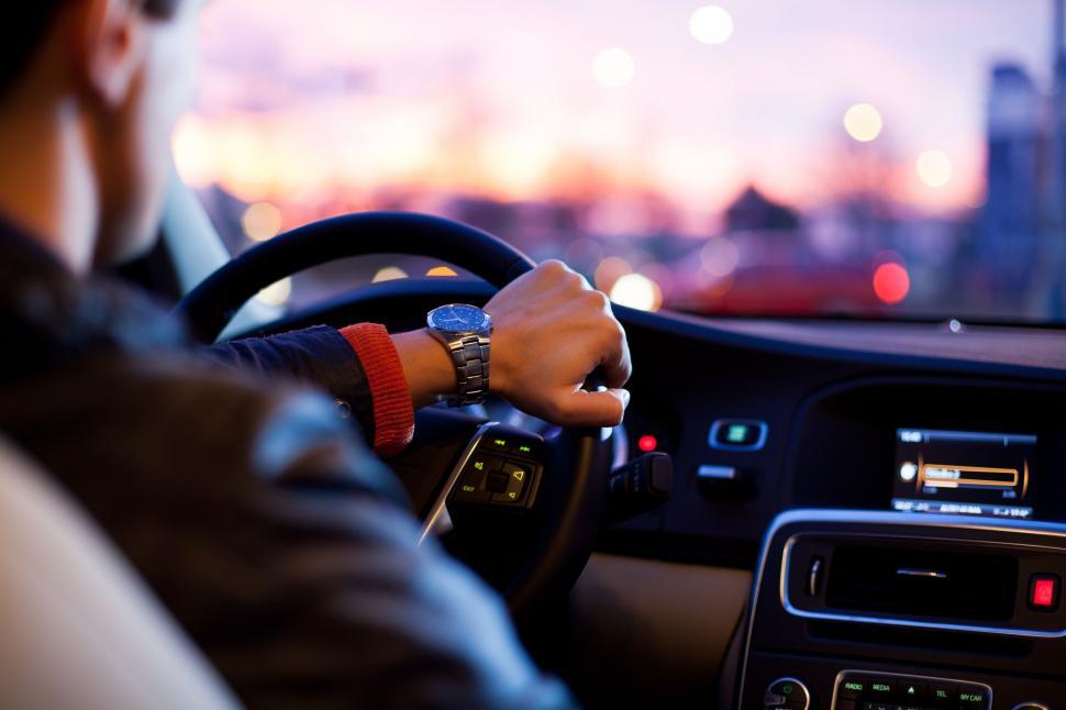 Free Image of Man Driving Car With City Background 