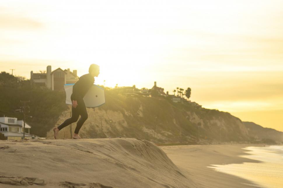 Free Image of Man Holding Surfboard on Sandy Beach 