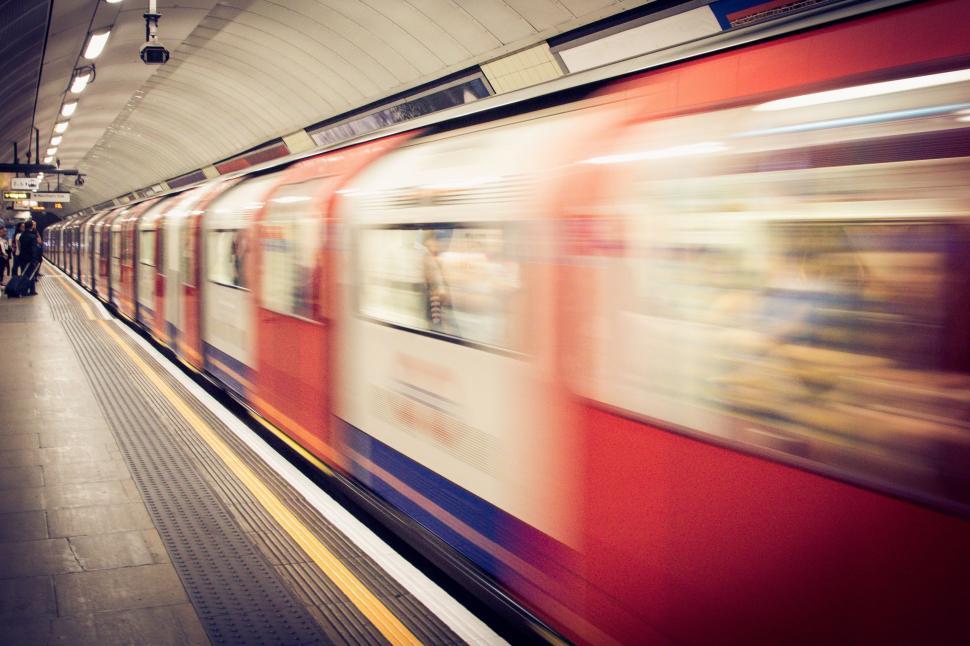 Free Image of Red Train Traveling Down Train Tracks Next to Loading Platform 