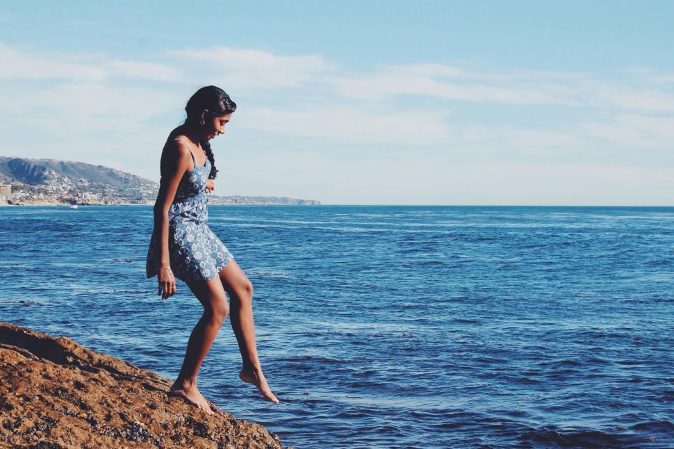 Free Image of Woman Standing on Rocky Beach Next to Ocean 