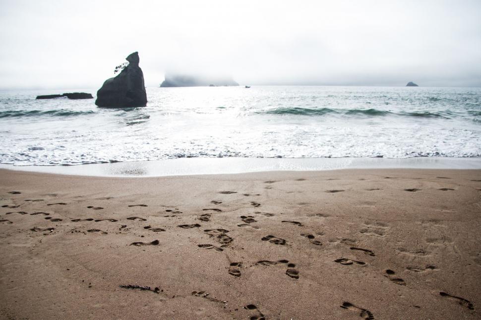 Free Image of Rock Jutting Out of Ocean Near Beach 