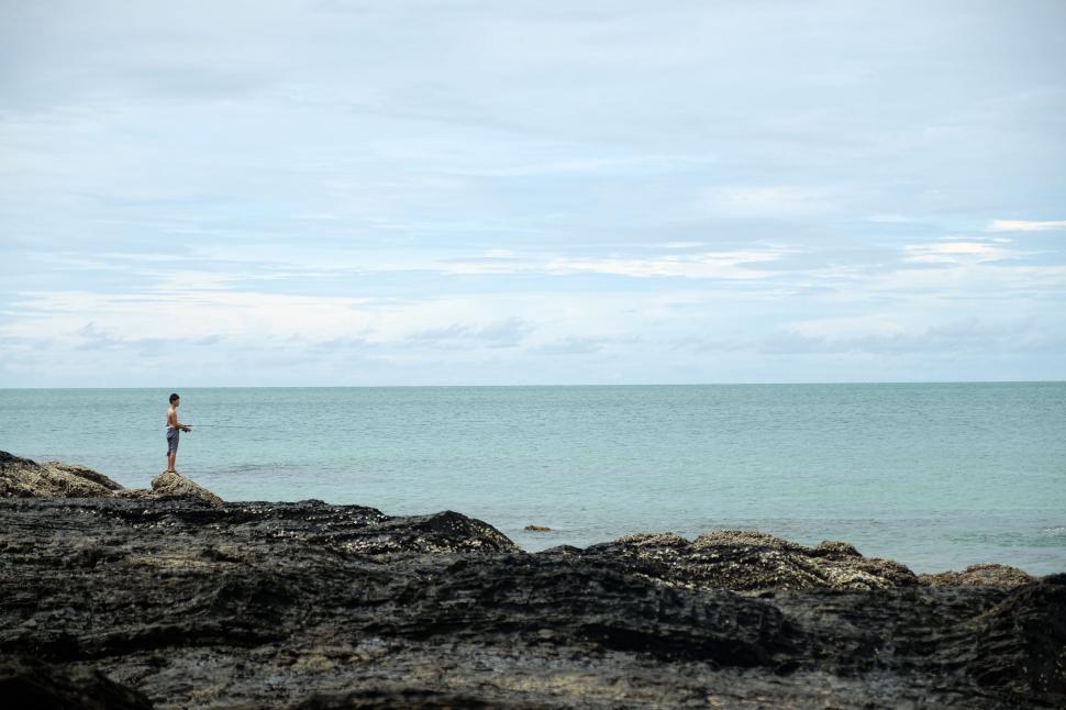 Free Image of Person Standing on Rocky Beach by the Ocean 