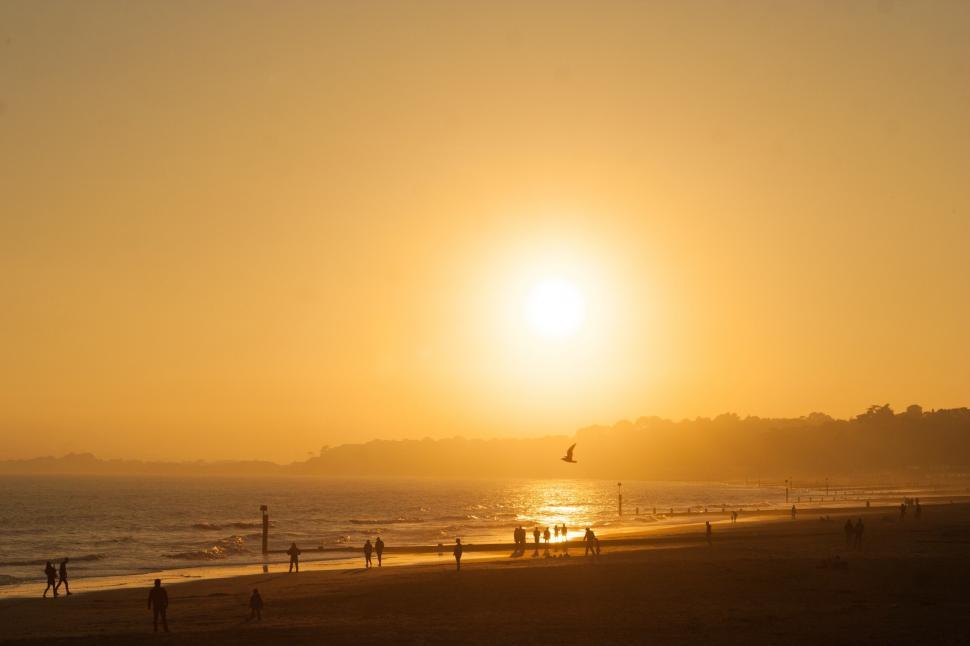 Free Image of People Walking on a Beach at Sunset 