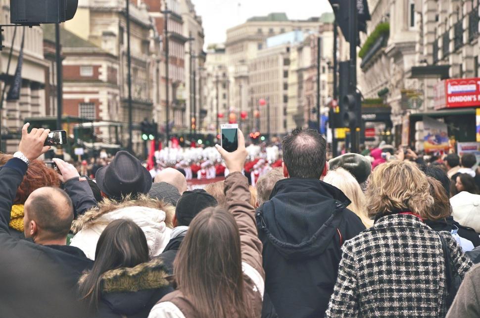 Free Image of Crowd of People Walking Down Street Next to Tall Buildings 