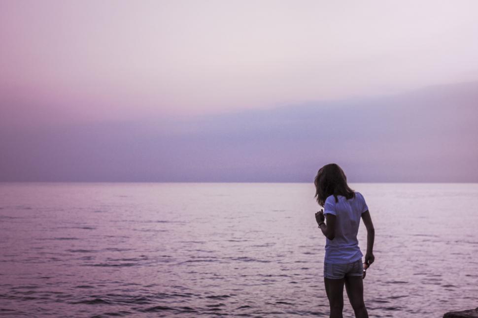 Free Image of Woman Standing on Rock by Ocean 