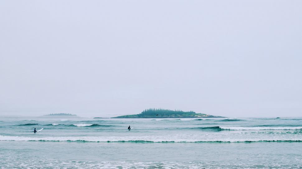 Free Image of Group of People Riding Surfboards on Top of a Wave 