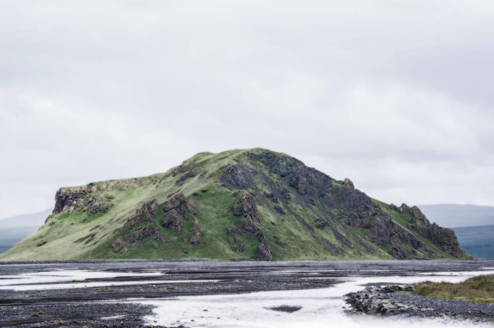 Free Image of Large Green Mountain in Middle of Body of Water 