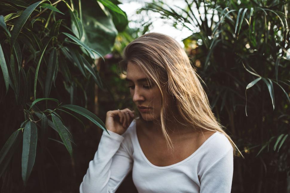 Free Image of Woman in White Shirt Standing in Front of Tree 