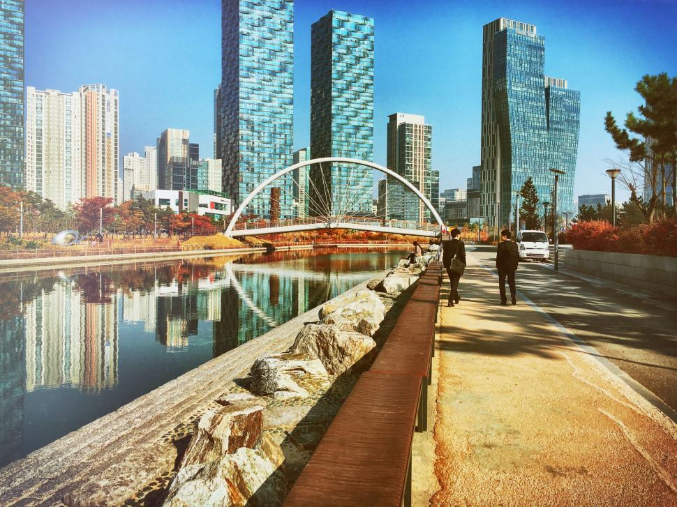 Free Image of Man Walking Down Sidewalk Along River 