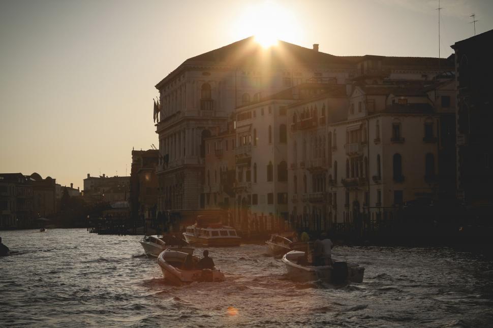 Free Image of Boats Floating Down River Next to Tall Building 