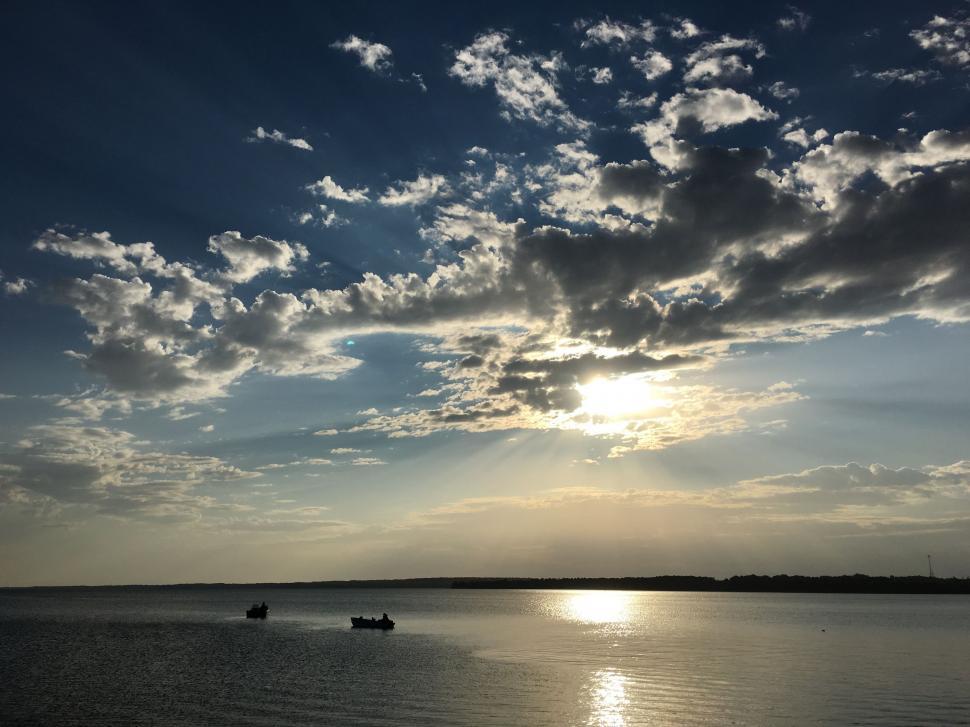 Free Image of Sun Shining Through Clouds Over Water 