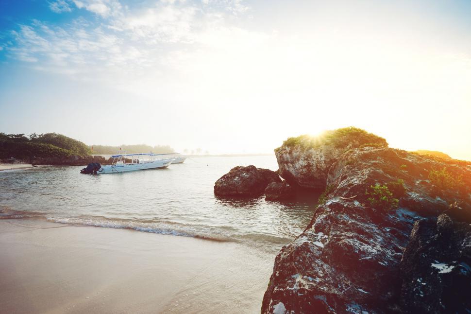 Free Image of Boat in Water Near Rock Outcropping on Beach 