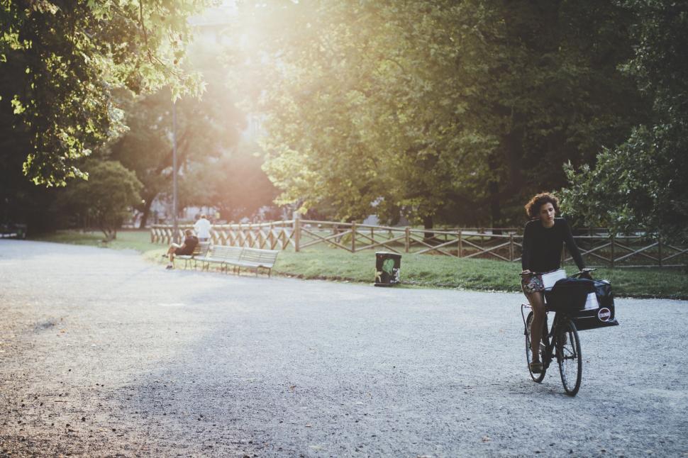 Free Image of Woman Riding Bike Down Gravel Road 