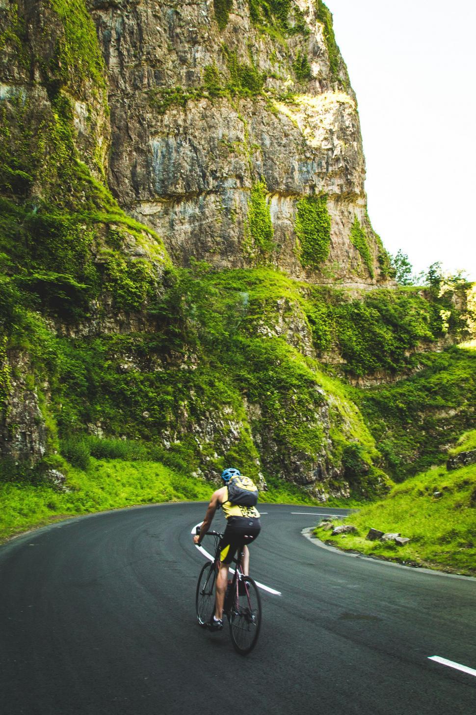 Free Image of Man Riding Bike Down Curvy Road 