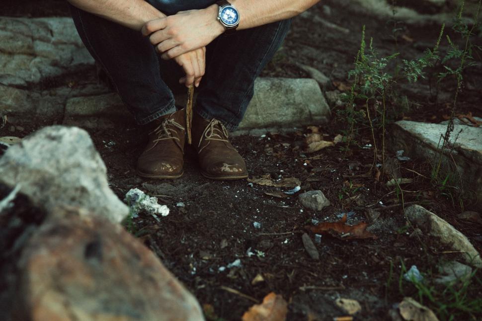 Free Image of Man Sitting on Ground With Hands on Knees 