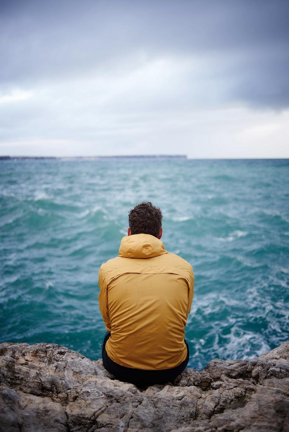 Free Image of Man Sitting on Rock, Looking at Ocean 